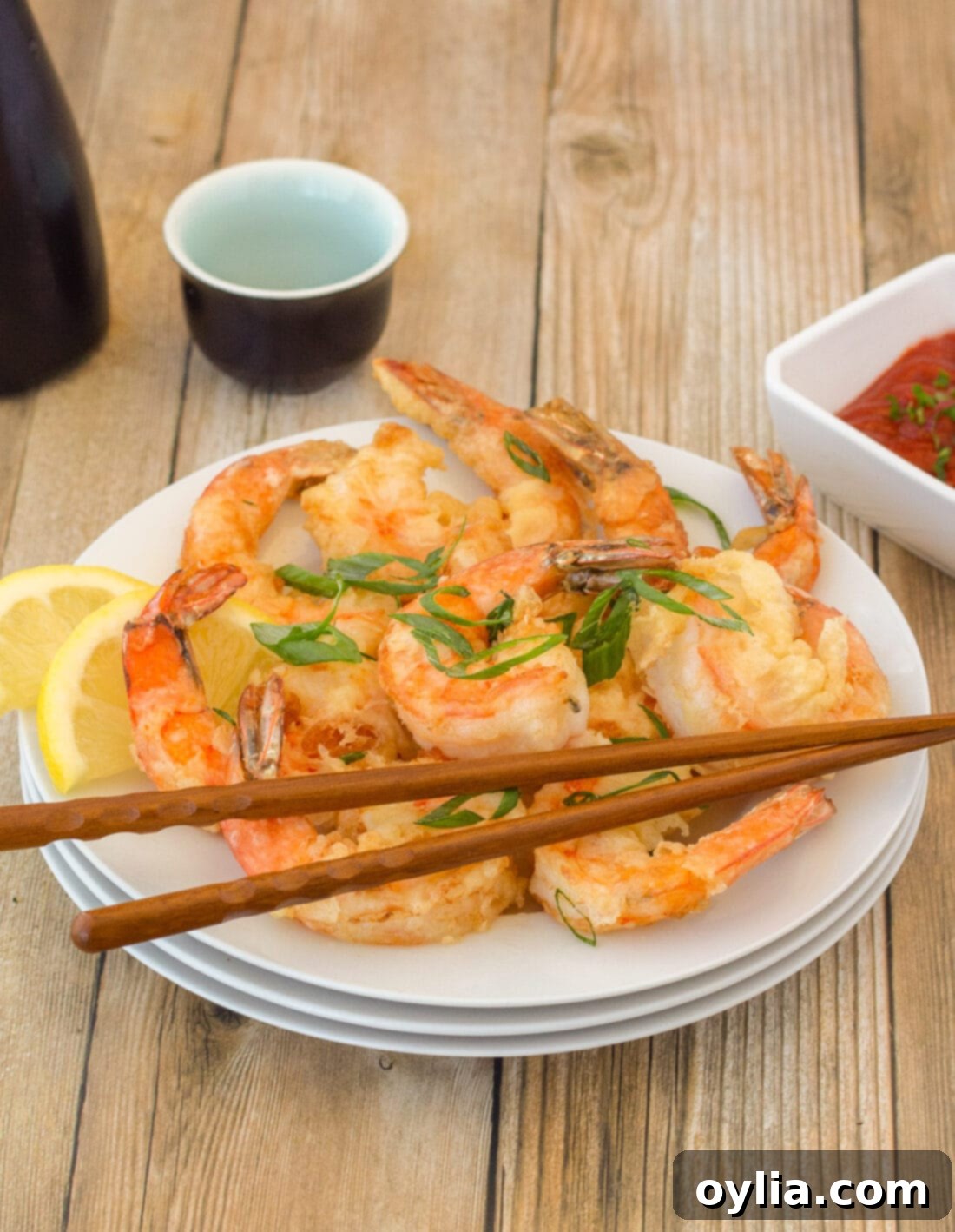 Plate of perfectly golden-brown crispy shrimp with chopsticks, ready to be enjoyed.
