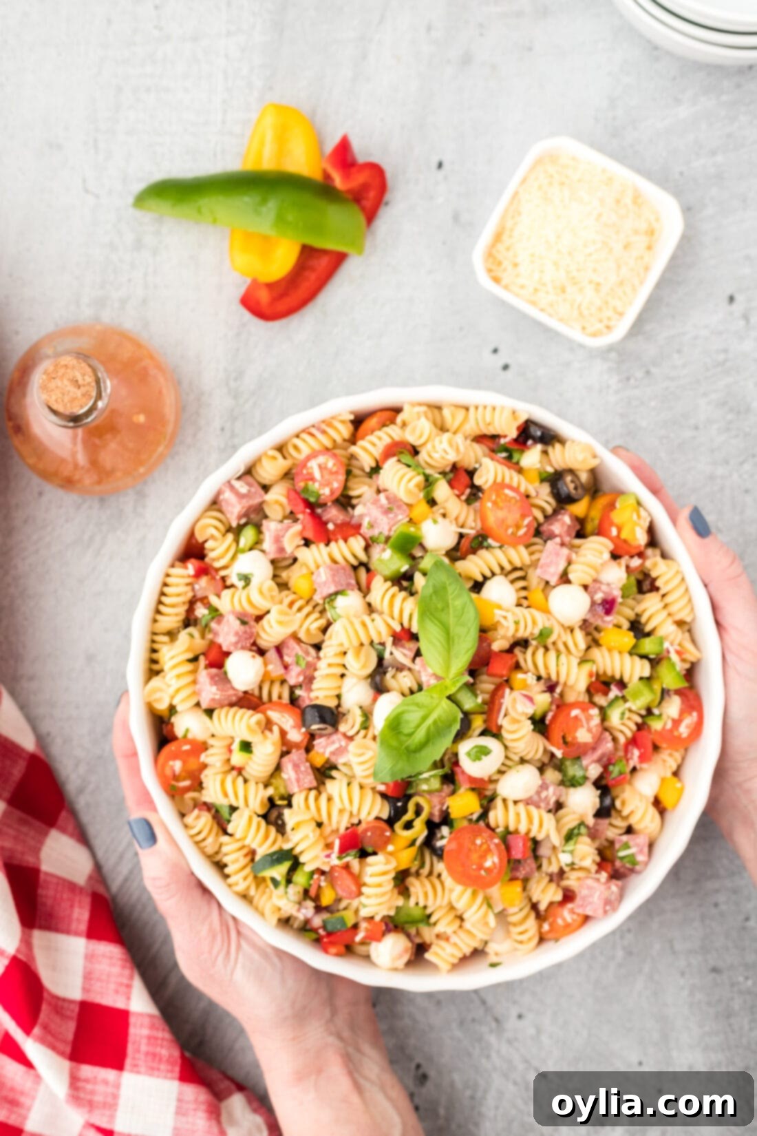hands picking up a bowl of Italian Pasta Salad from a picnic spread