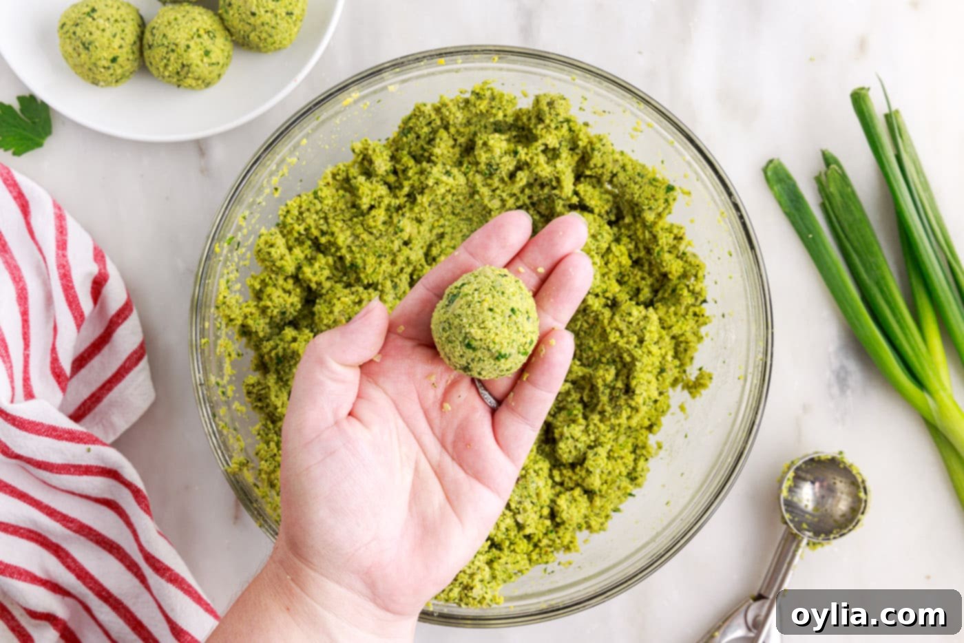 A freshly formed falafel ball being held in a hand, showing its smooth, round shape.