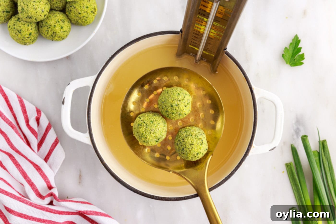 Falafel balls actively frying and bubbling in hot oil within a deep pot.