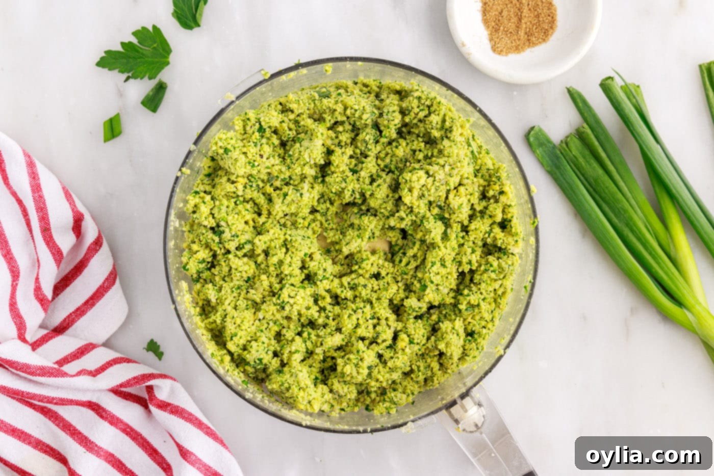 Close-up of falafel mixture in a food processor, showing a coarse, sandy texture.