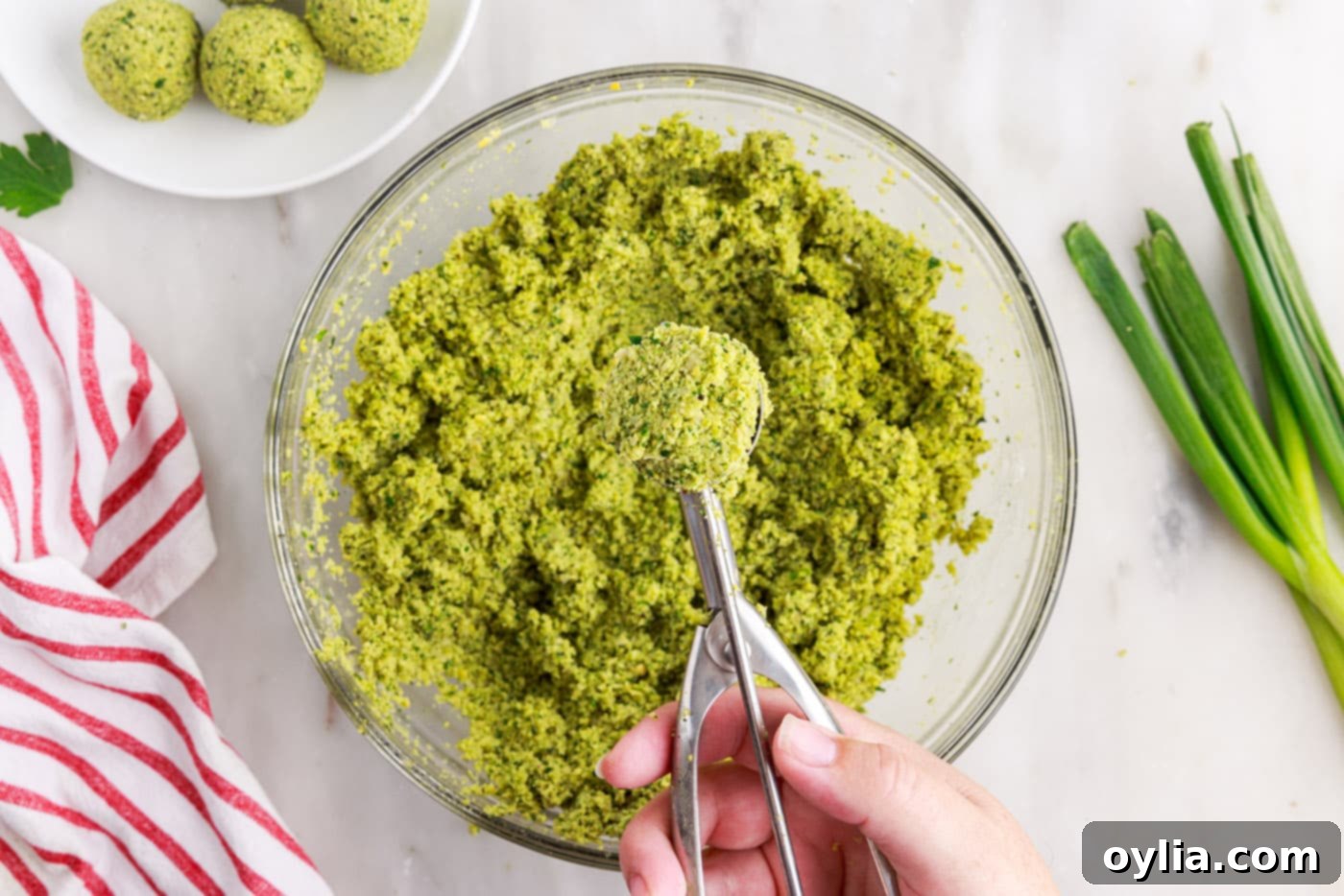 A cookie scoop measuring out a portion of falafel mixture.