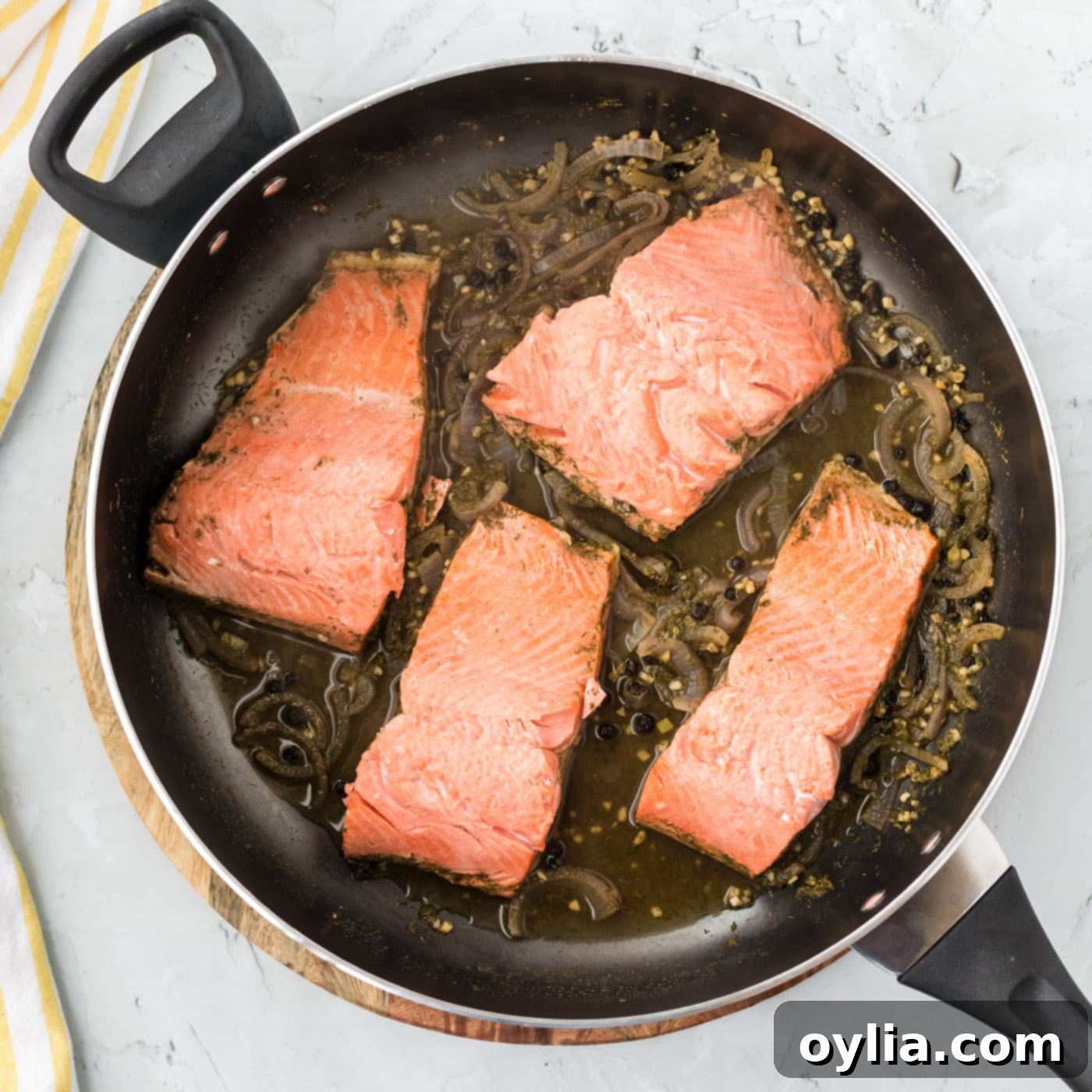 poached salmon in a skillet with aromatic liquid