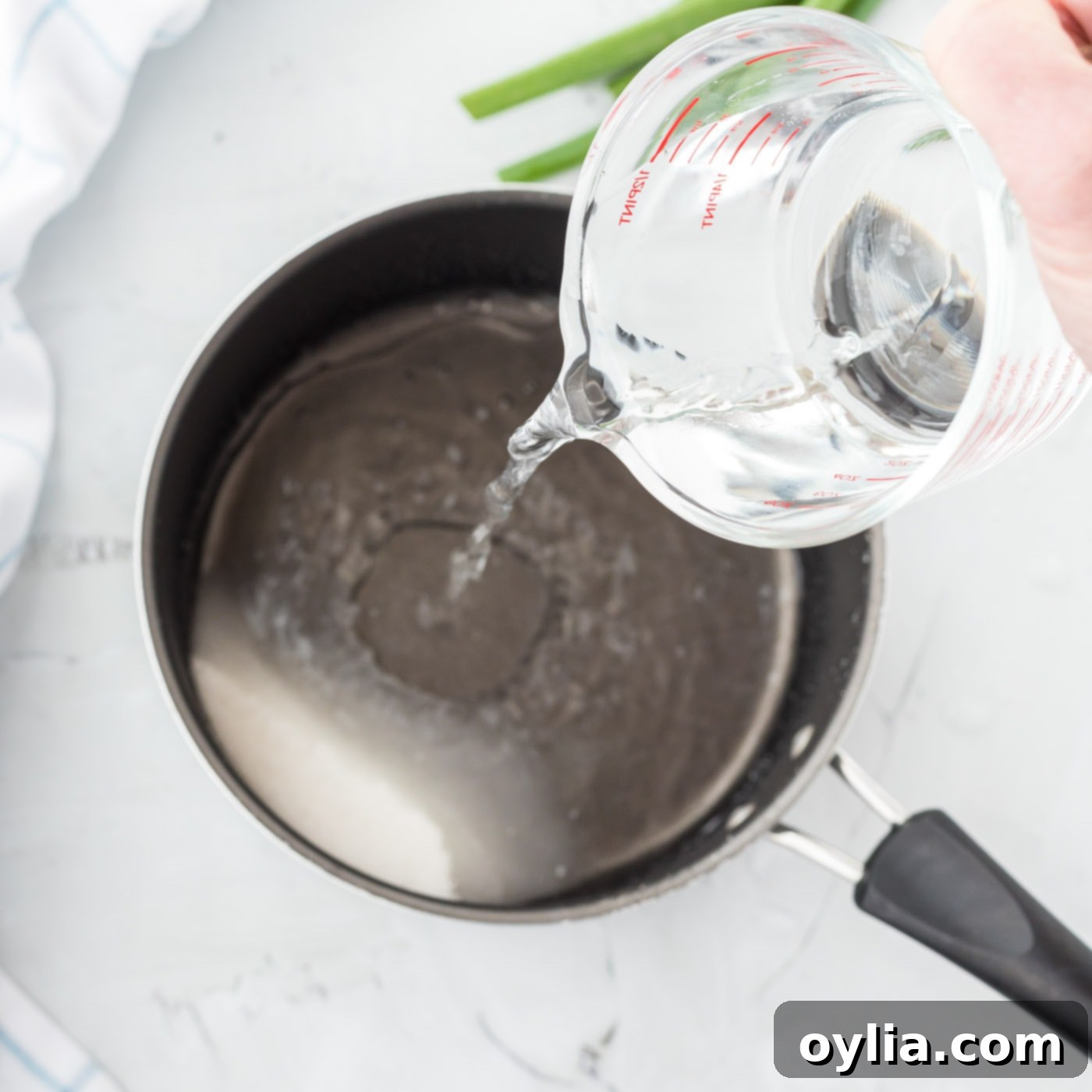 Sugar and water boiling in a saucepan with walnuts added.