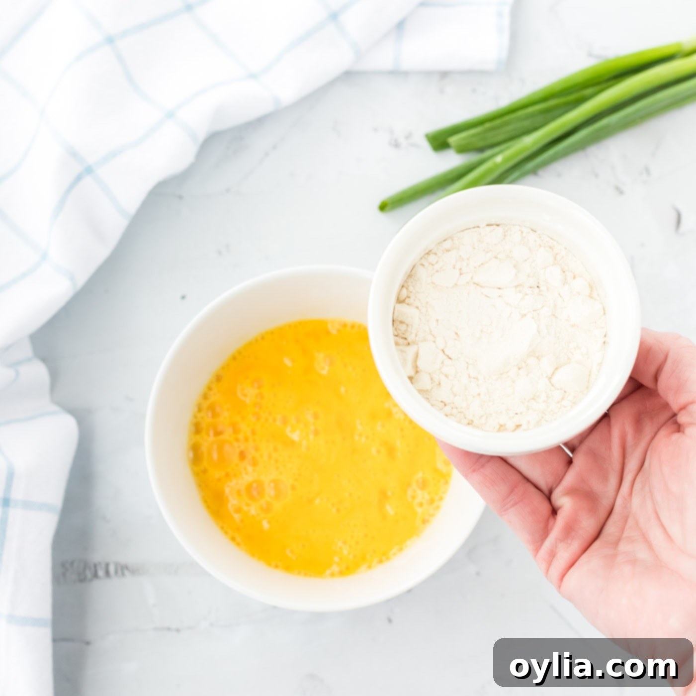 A bowl of whisked egg and a bowl of flour, prepared for shrimp battering.