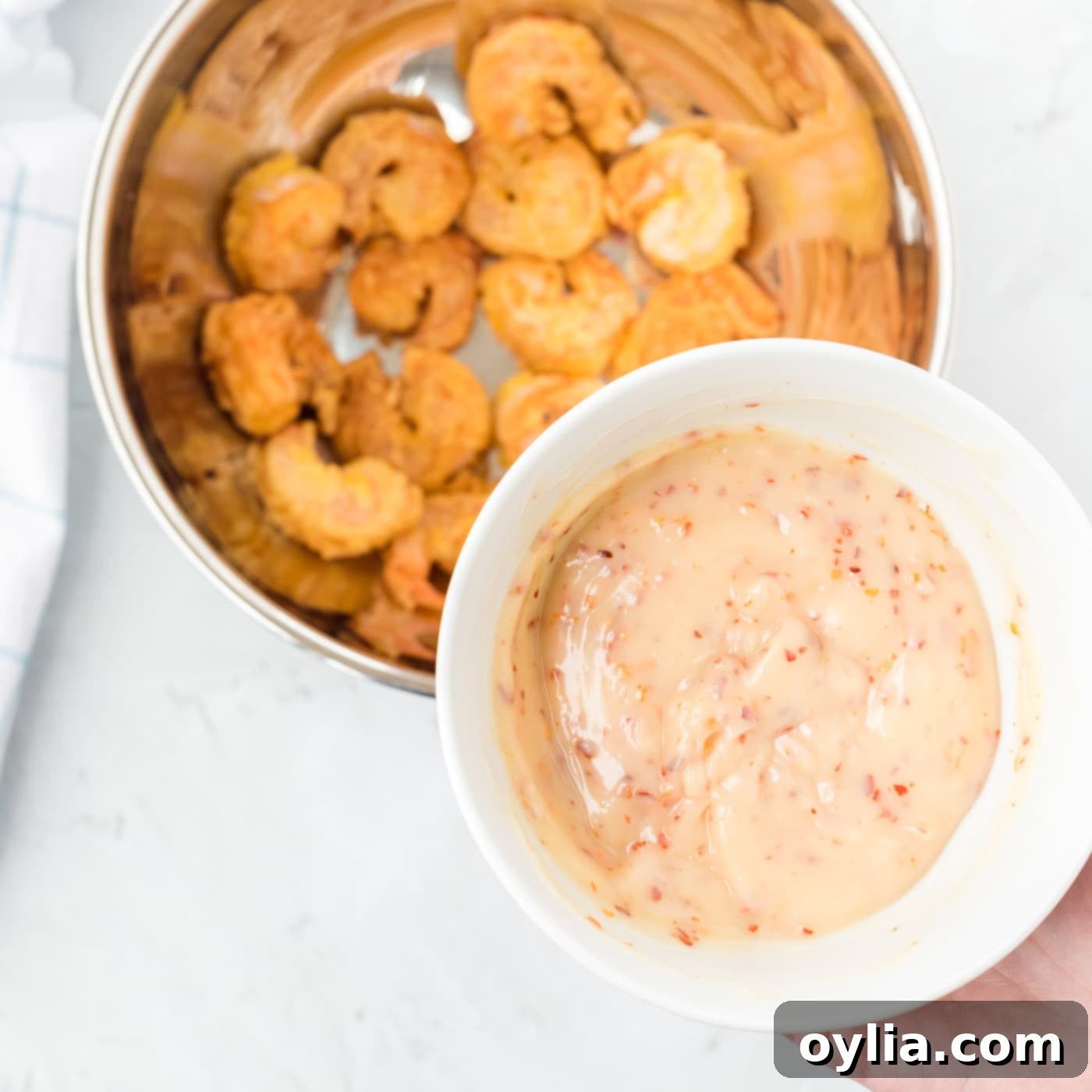 Crispy fried shrimp and candied walnuts being coated with honey sauce in a large bowl.
