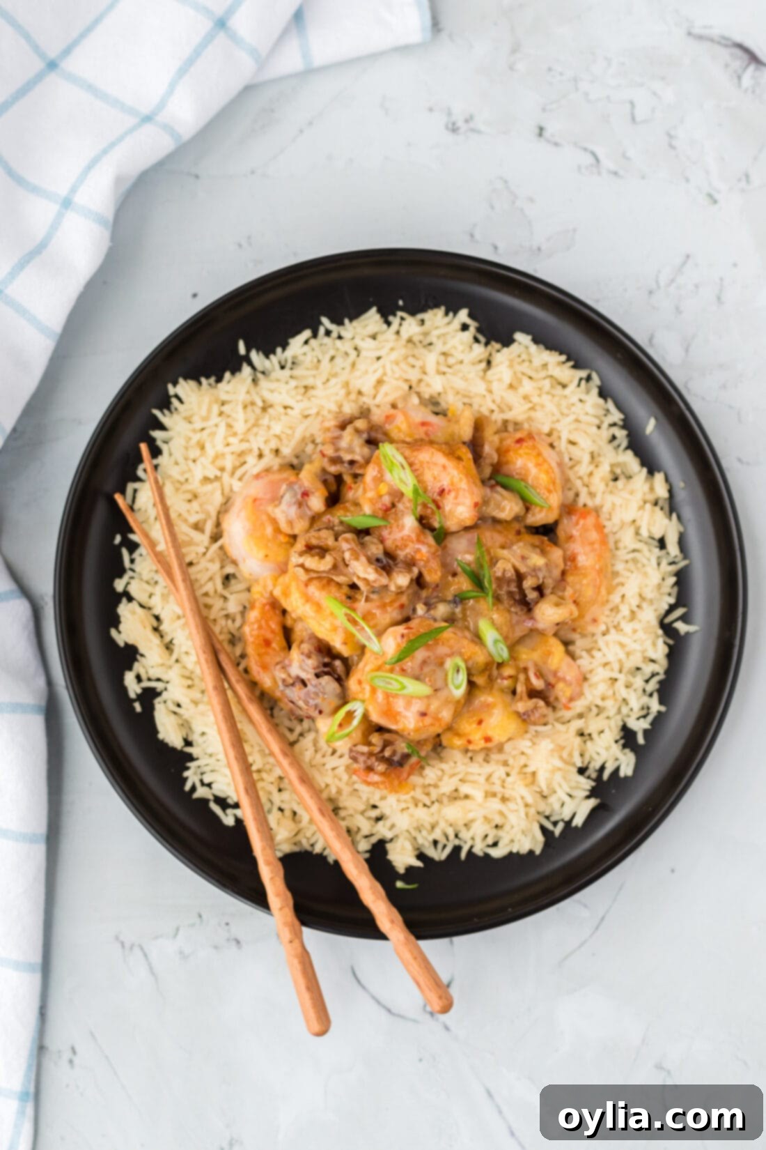Close-up of a plate of Honey Walnut Shrimp with rice, ready to be served, chopsticks nearby.