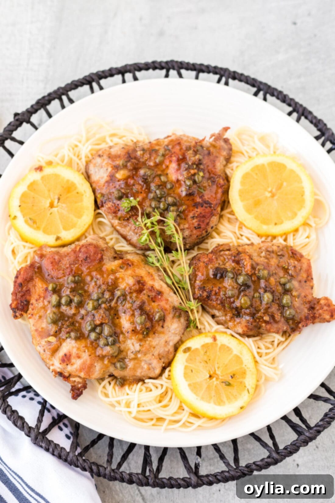 plate of Veal Piccata with lemon wedges and fresh thyme sprigs