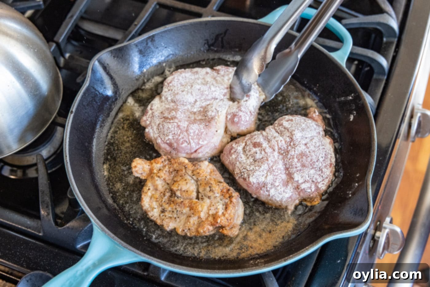 flipping flour dredged veal cutlets in a skillet to sear the other side
