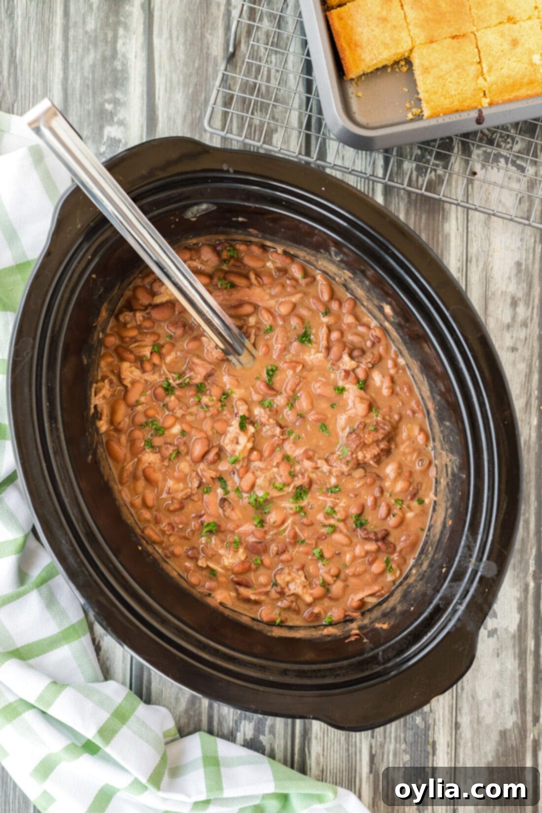 Ladle scooping tender slow cooker pinto beans from a crockpot