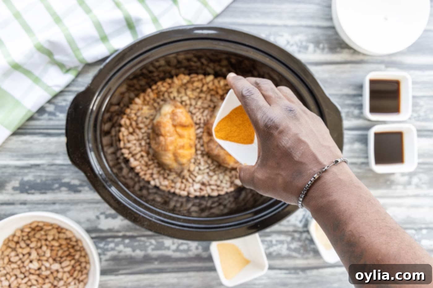 Sprinkling additional seasonings over turkey tails and pinto beans