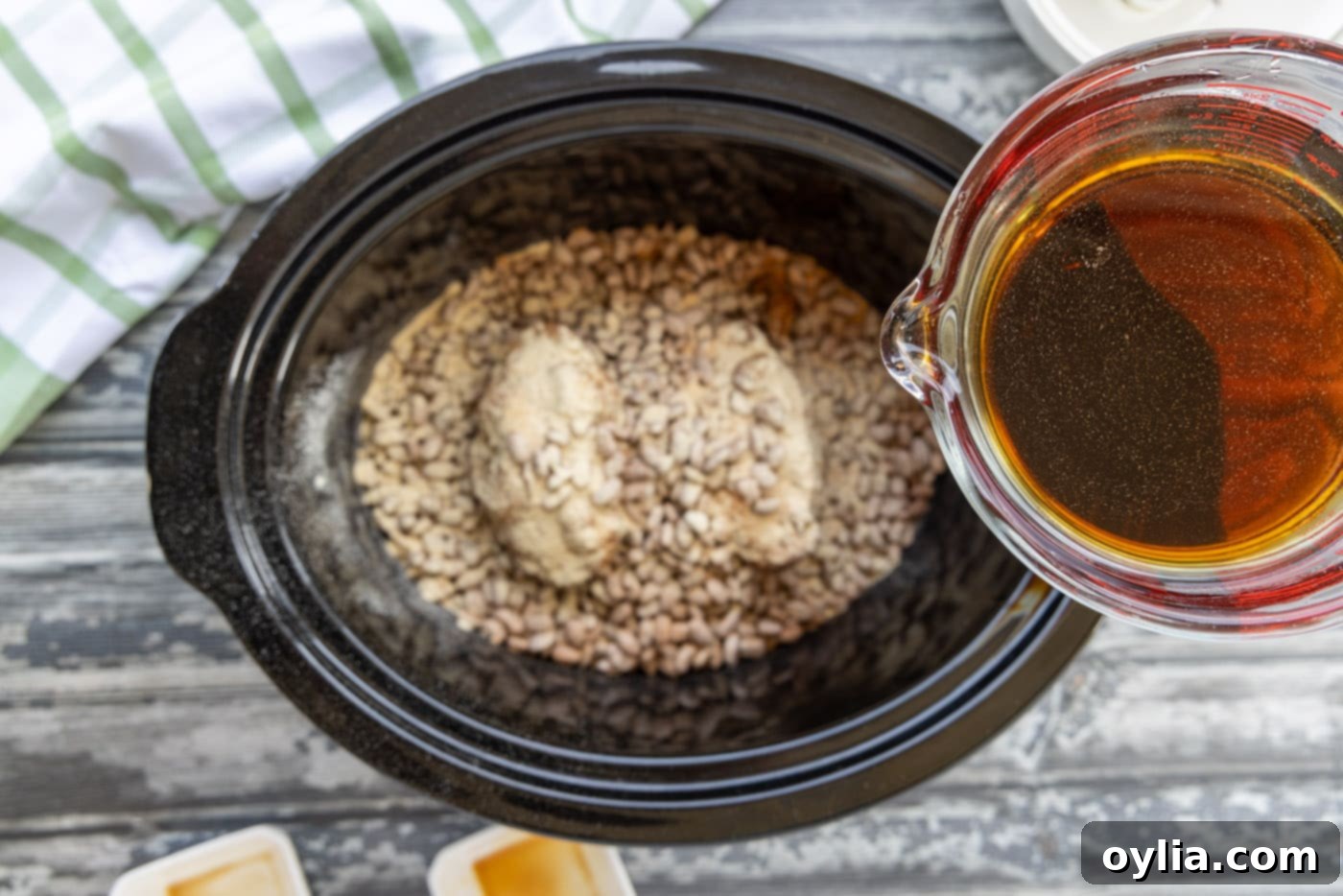 Pouring liquid smoke, soy sauce, and water over pinto beans and turkey tails