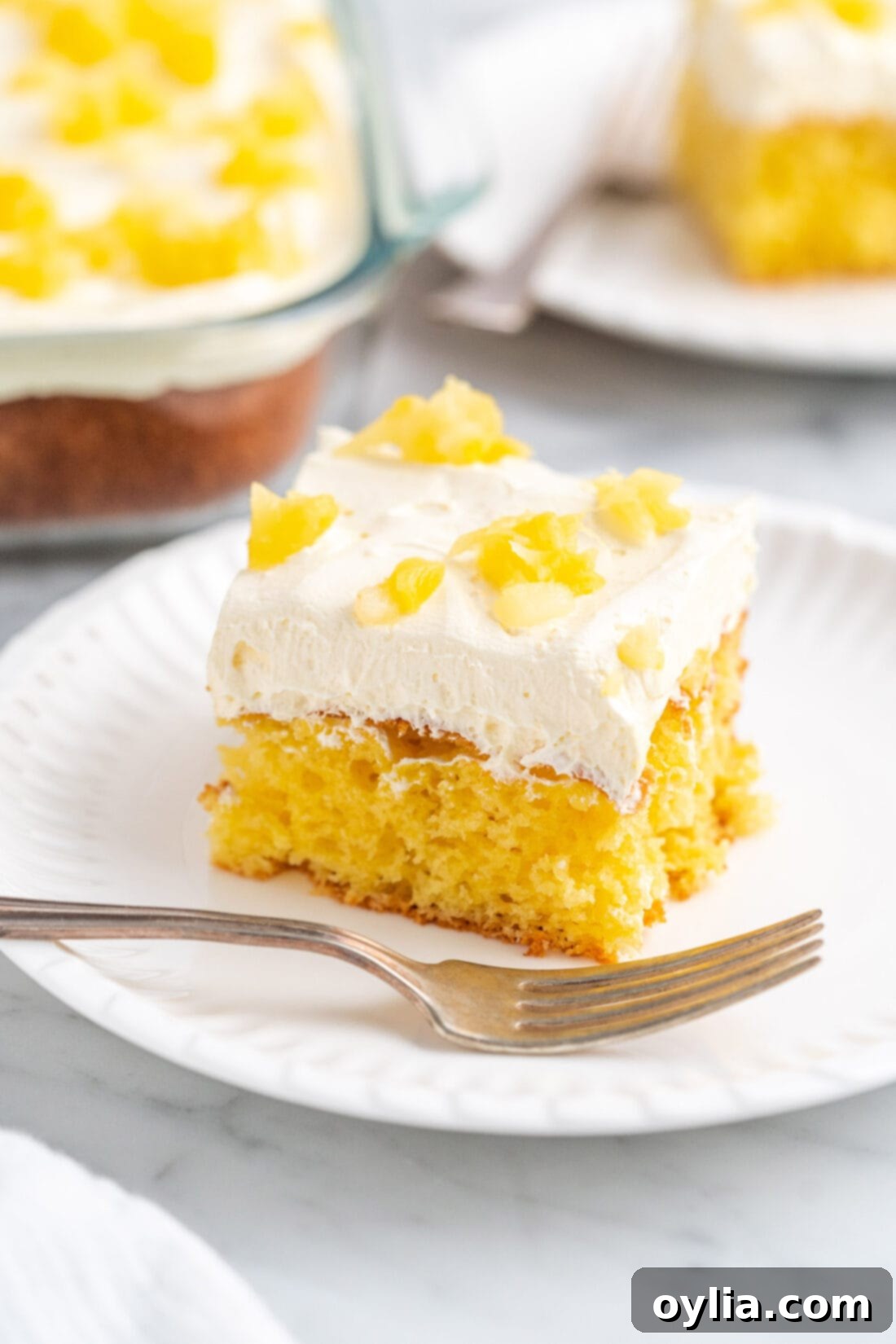 Slice of Fluffy Pineapple Sunshine Cake on a plate, showing its moist texture and whipped frosting