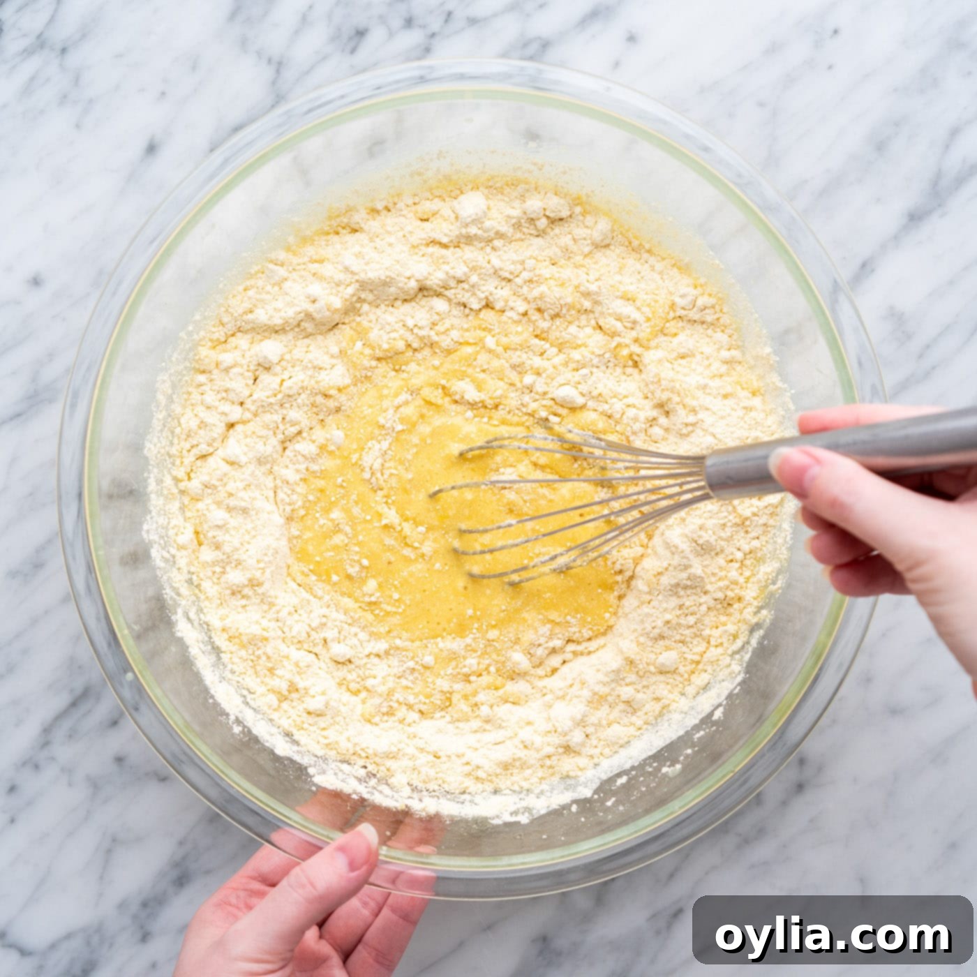 Whisking yellow cake mix with crushed pineapple, eggs, and oil in a large bowl
