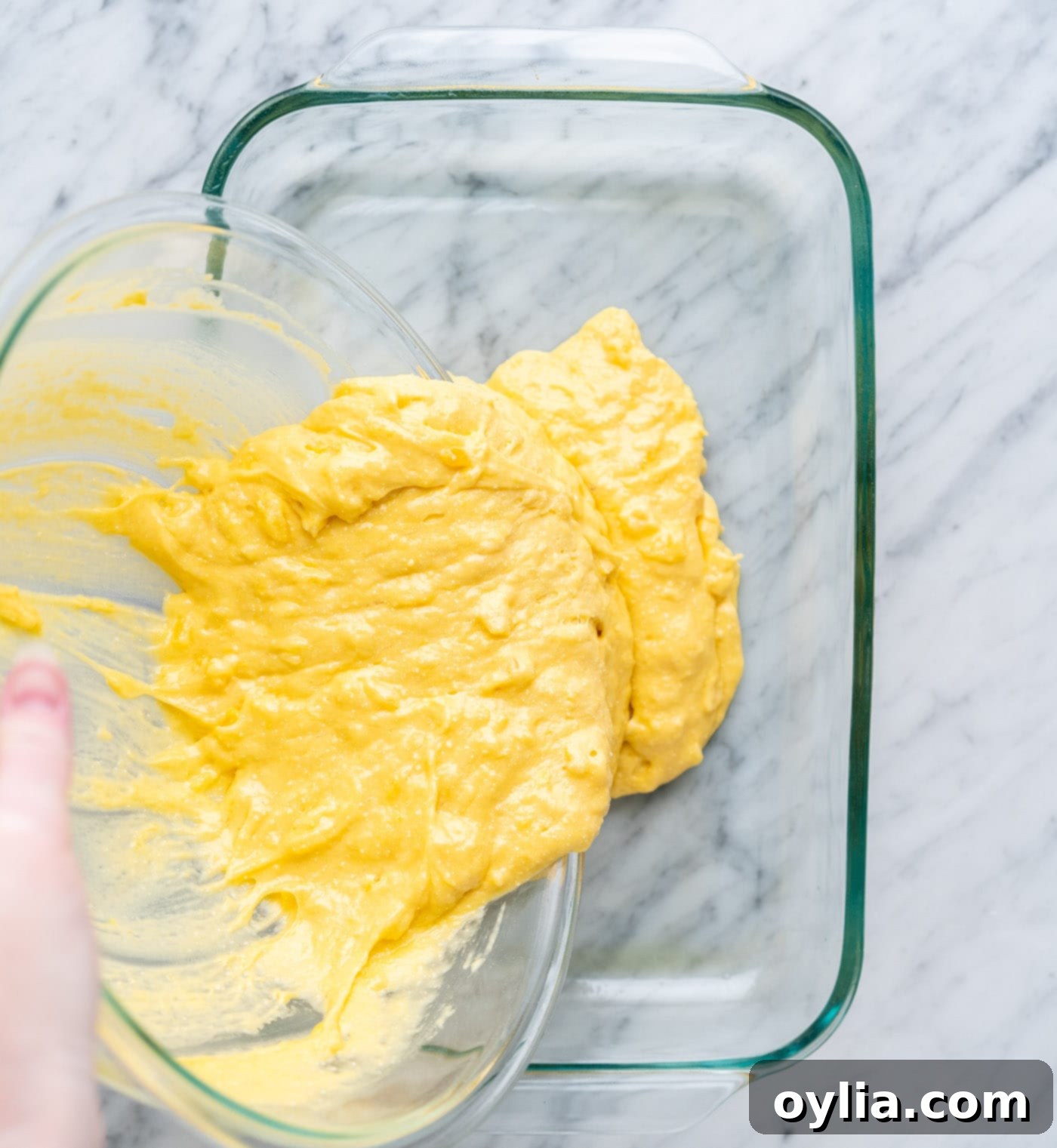Pouring pineapple cake batter into a nonstick-sprayed baking dish