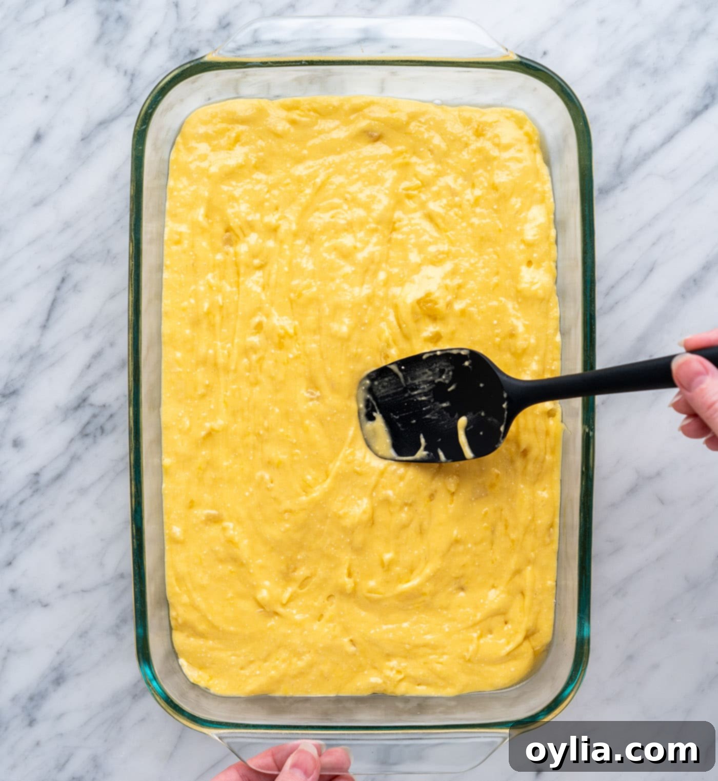 Spreading pineapple cake batter evenly in a 9x13 inch baking dish