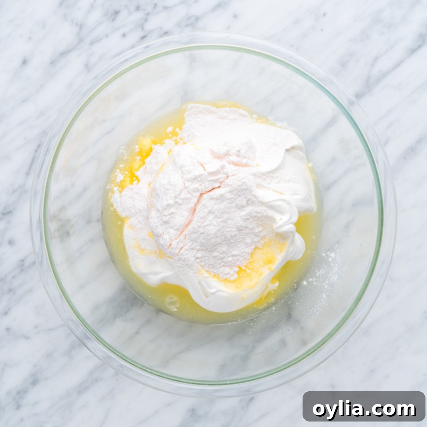 Mixing pineapple juice, whipped cream, and dry vanilla pudding mix for frosting