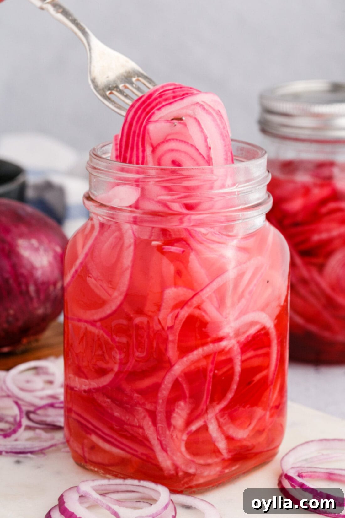 Vinegar-Kissed Onions 2 Lifting vibrant pink pickled red onions with a fork, ready to serve