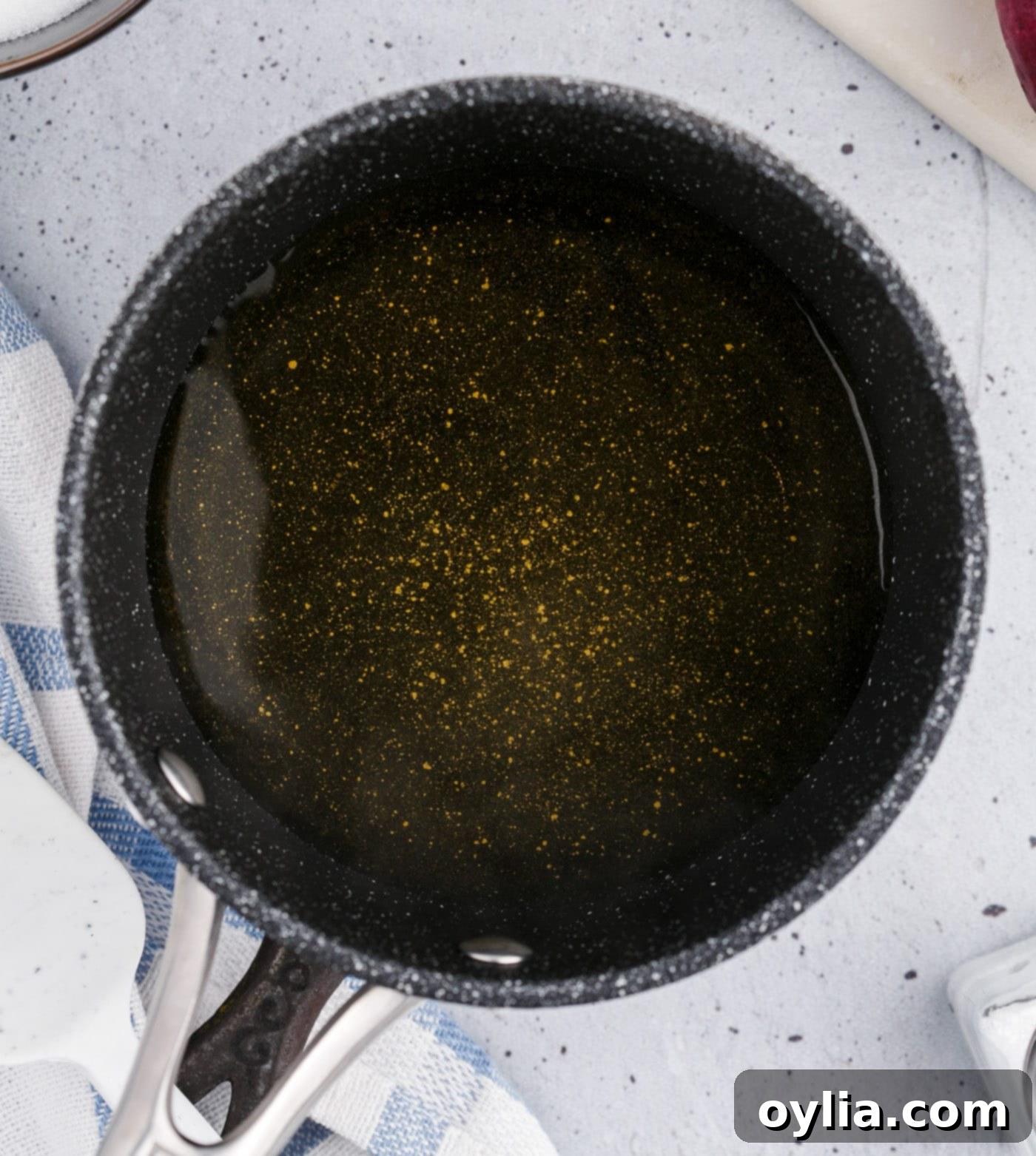 Close-up of the clear, simmering pickled onion vinegar mixture in a saucepan
