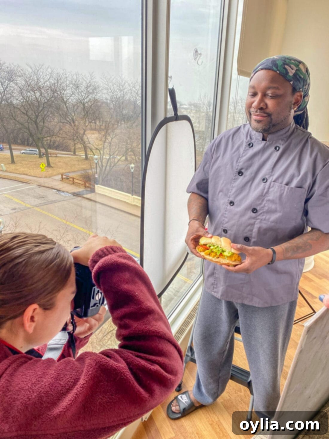 Chef Antoine posing with a large, delicious Shrimp Po Boy sandwich, demonstrating its impressive size and presentation.