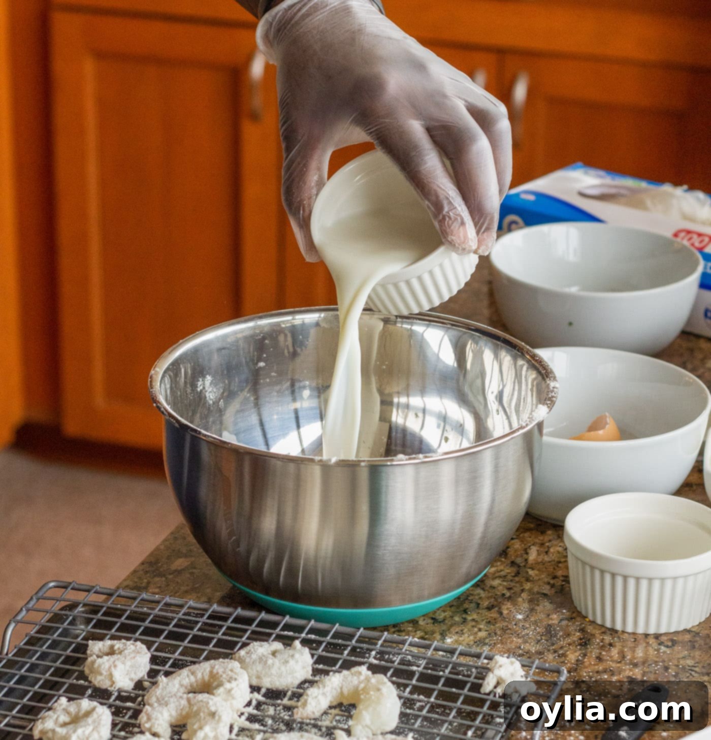 Pouring milk into the egg and seasoning mixture for the shrimp breading.