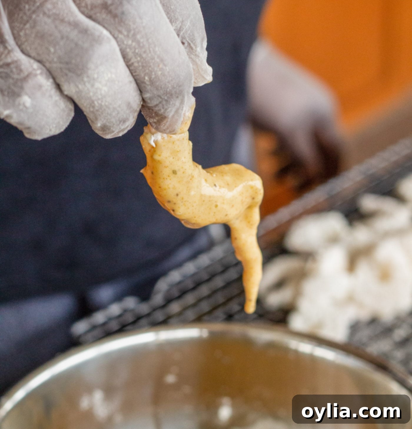 Dipping flour-coated shrimp into the seasoned egg mixture.