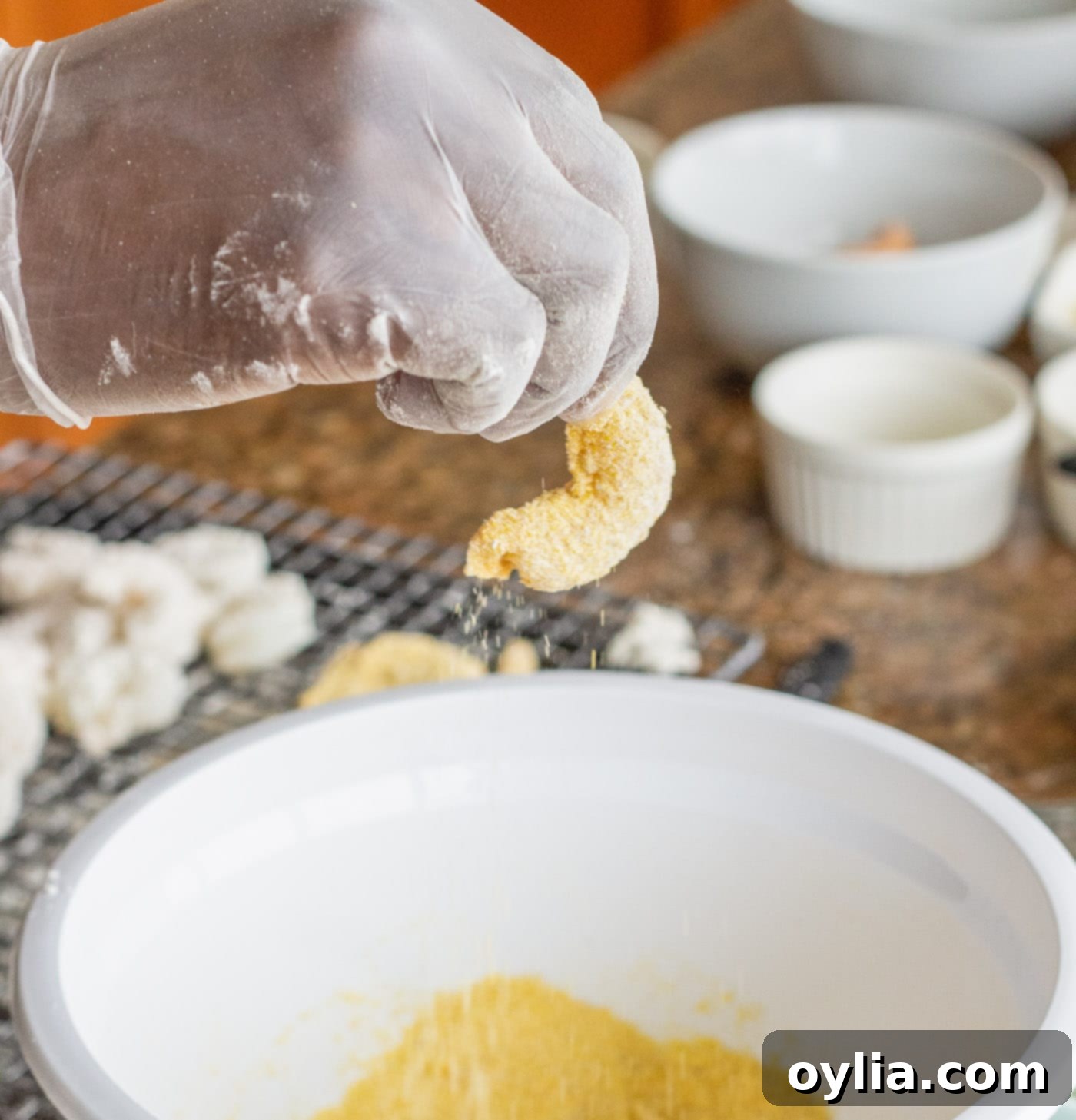 Dredging shrimp, already coated in flour and egg wash, into cornmeal for the final crispy layer.
