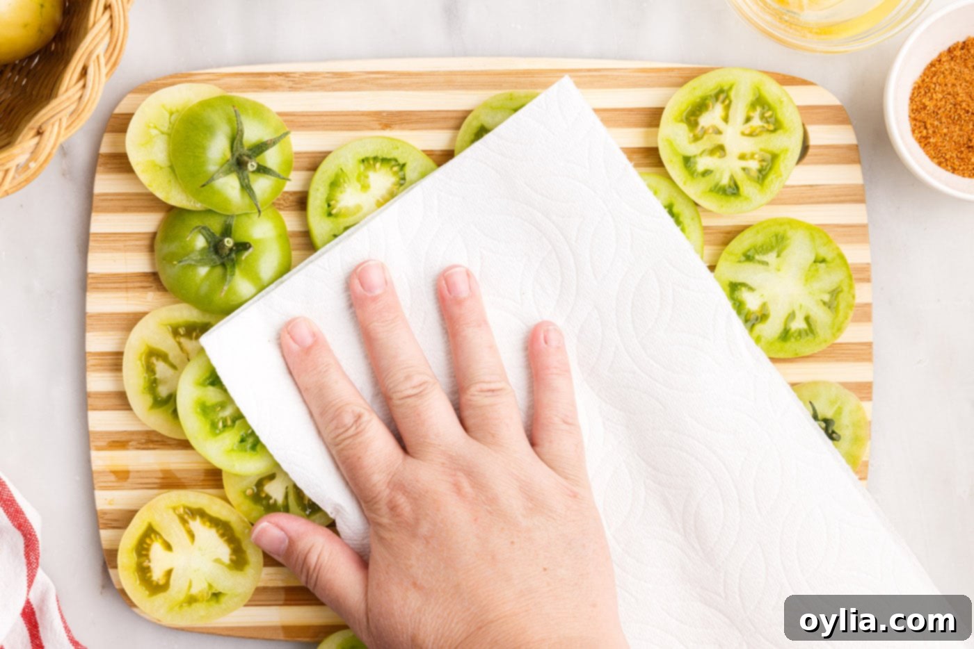 patting sliced green tomatoes dry with a paper towel