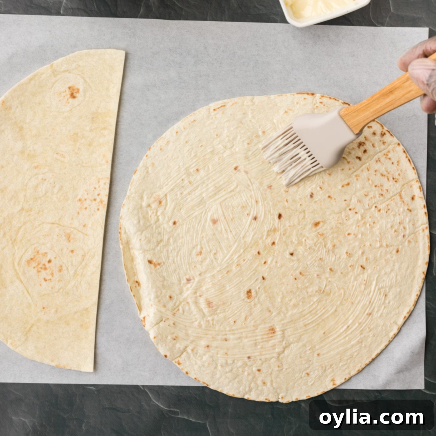 brushing on softened butter to tortilla