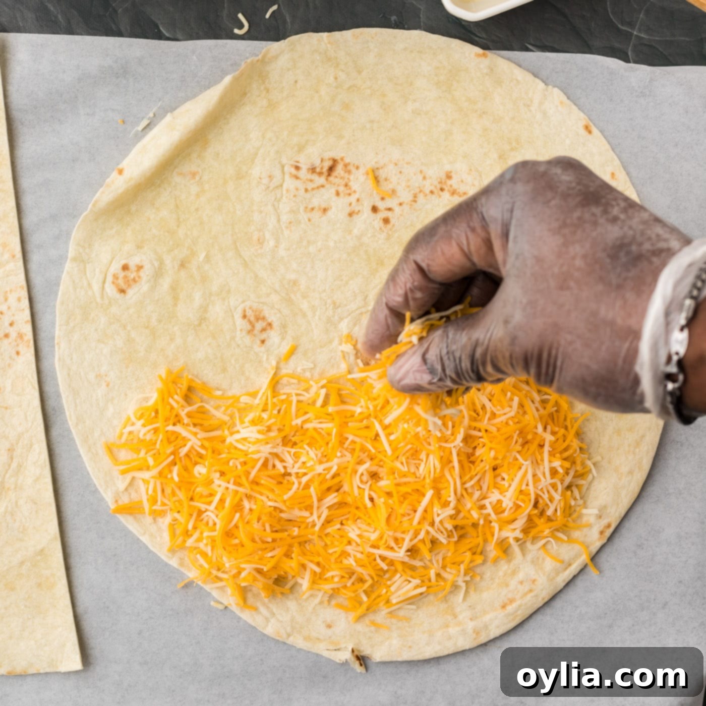 sprinkling cheese on flour tortilla