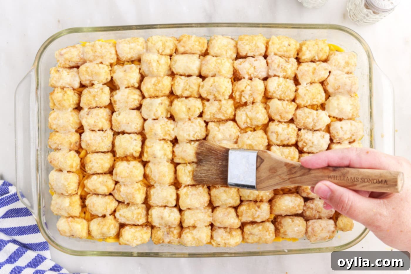 brushing melted butter over tatertots