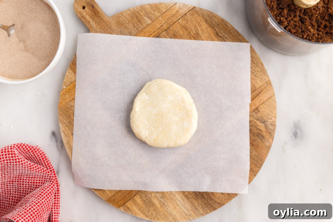 A disc of rugelach dough placed on parchment paper, ready for rolling.