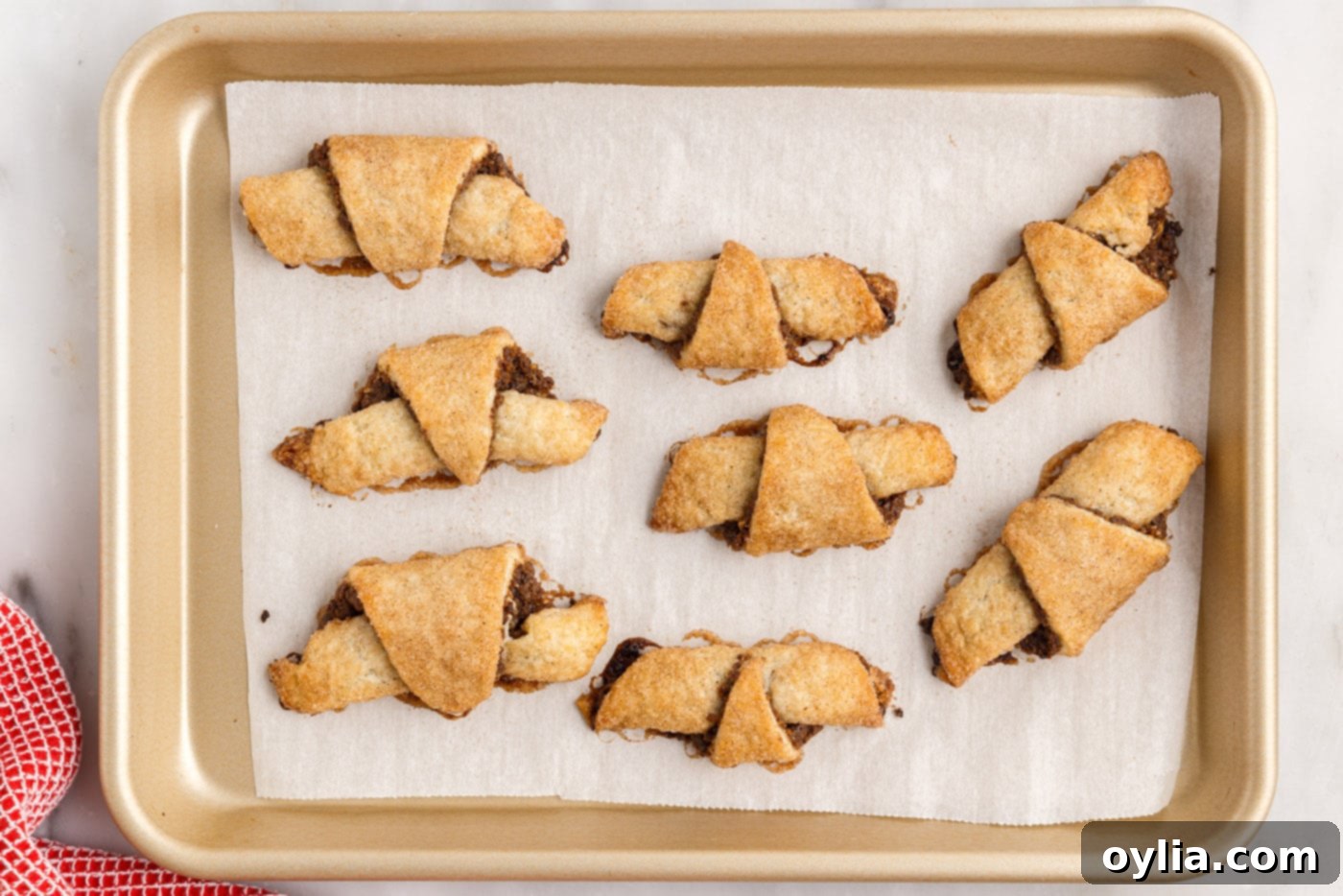 Freshly baked cinnamon raisin rugelach, golden brown and tempting, on a cooling rack.