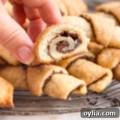 Rugelach cookie with a bite taken out, showing the filling and flaky layers.