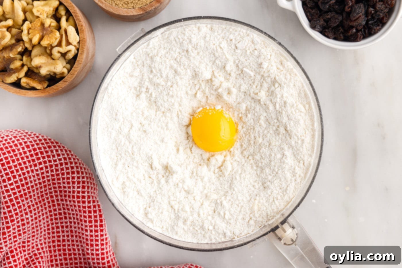 An egg yolk added to the crumbly cream cheese dough mixture in a food processor.