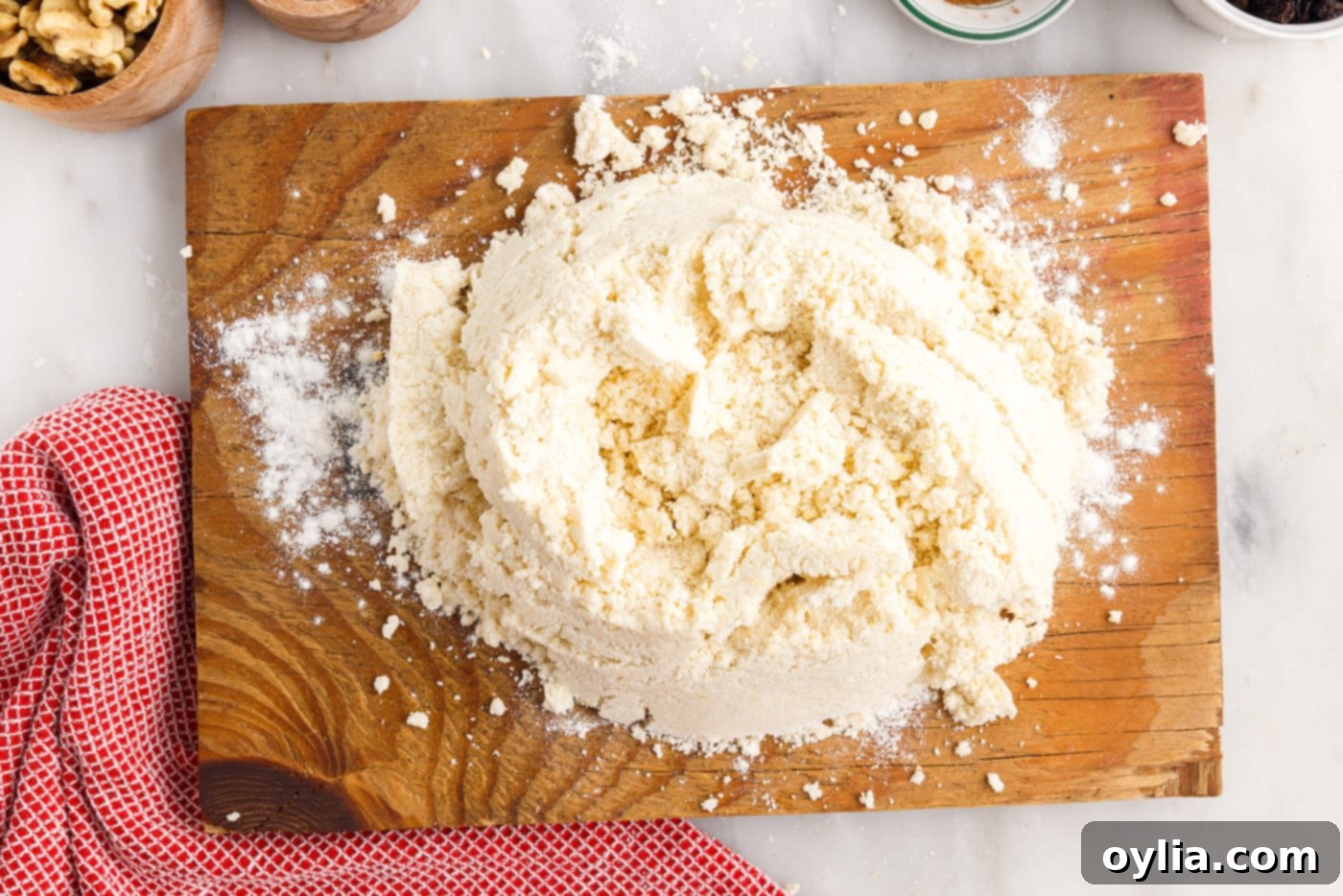 Rugelach dough being gathered into a ball on a lightly floured cutting board.