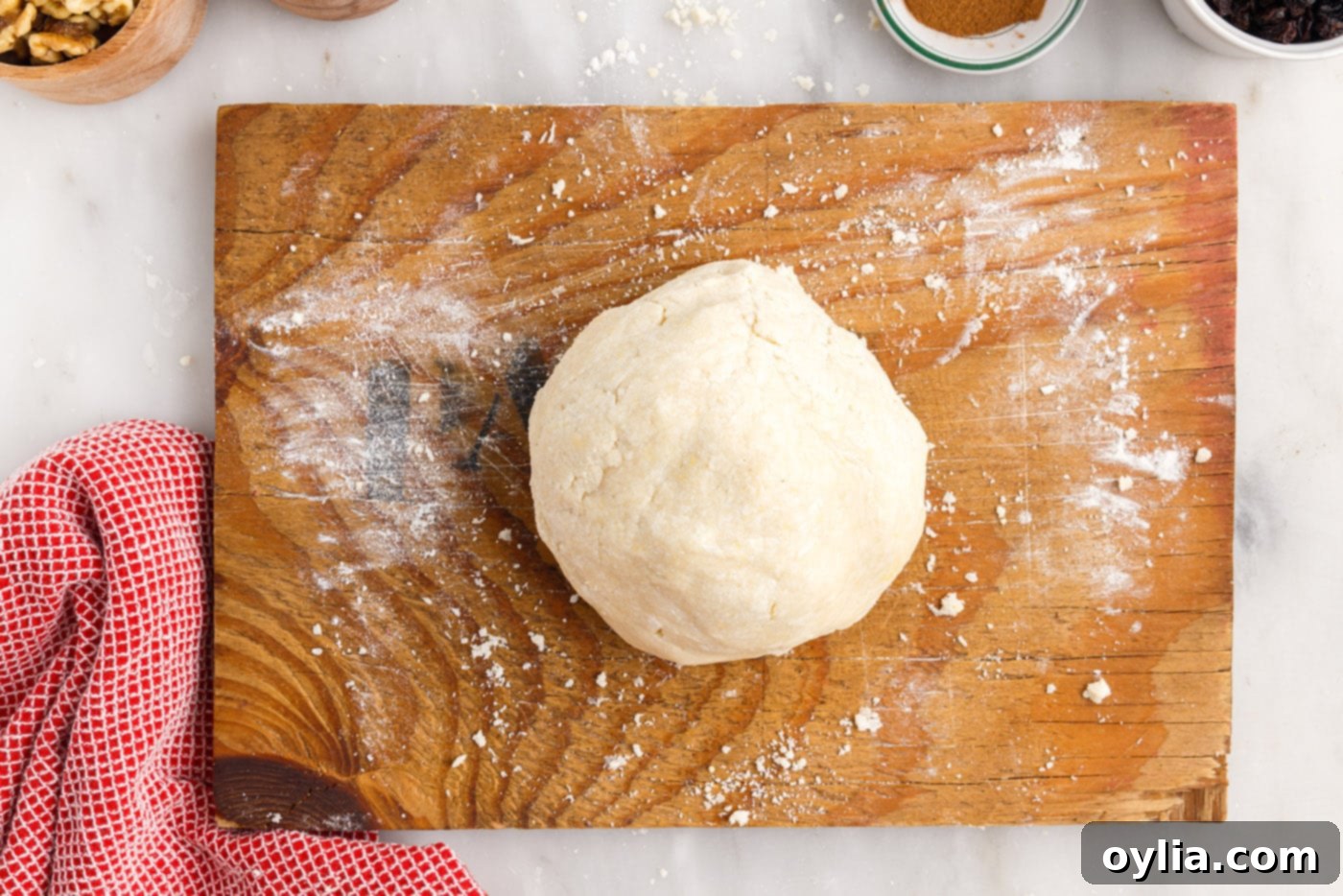 A smooth ball of rugelach dough resting on a cutting board.
