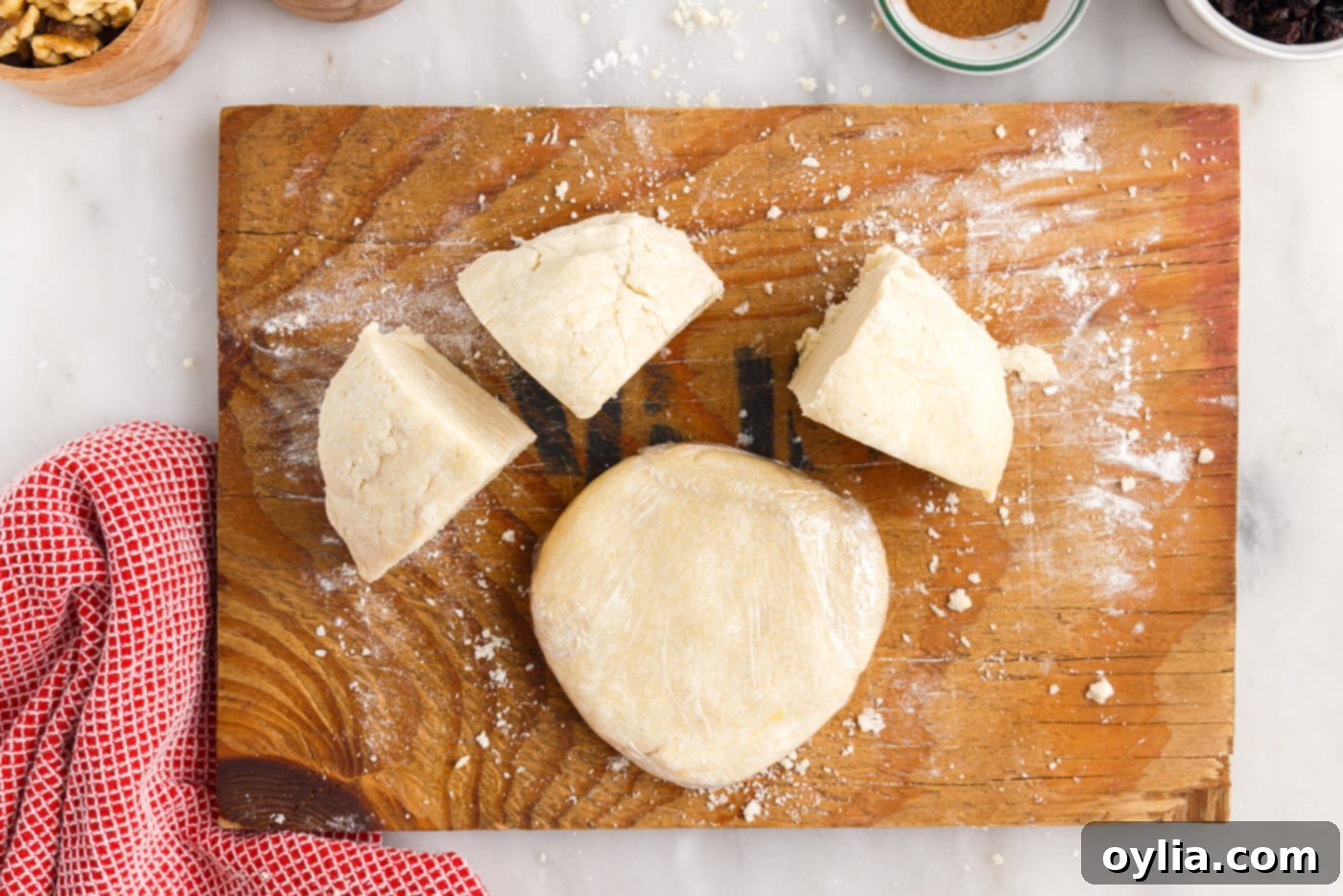 Rugelach dough being cut into four equal portions on a cutting board.