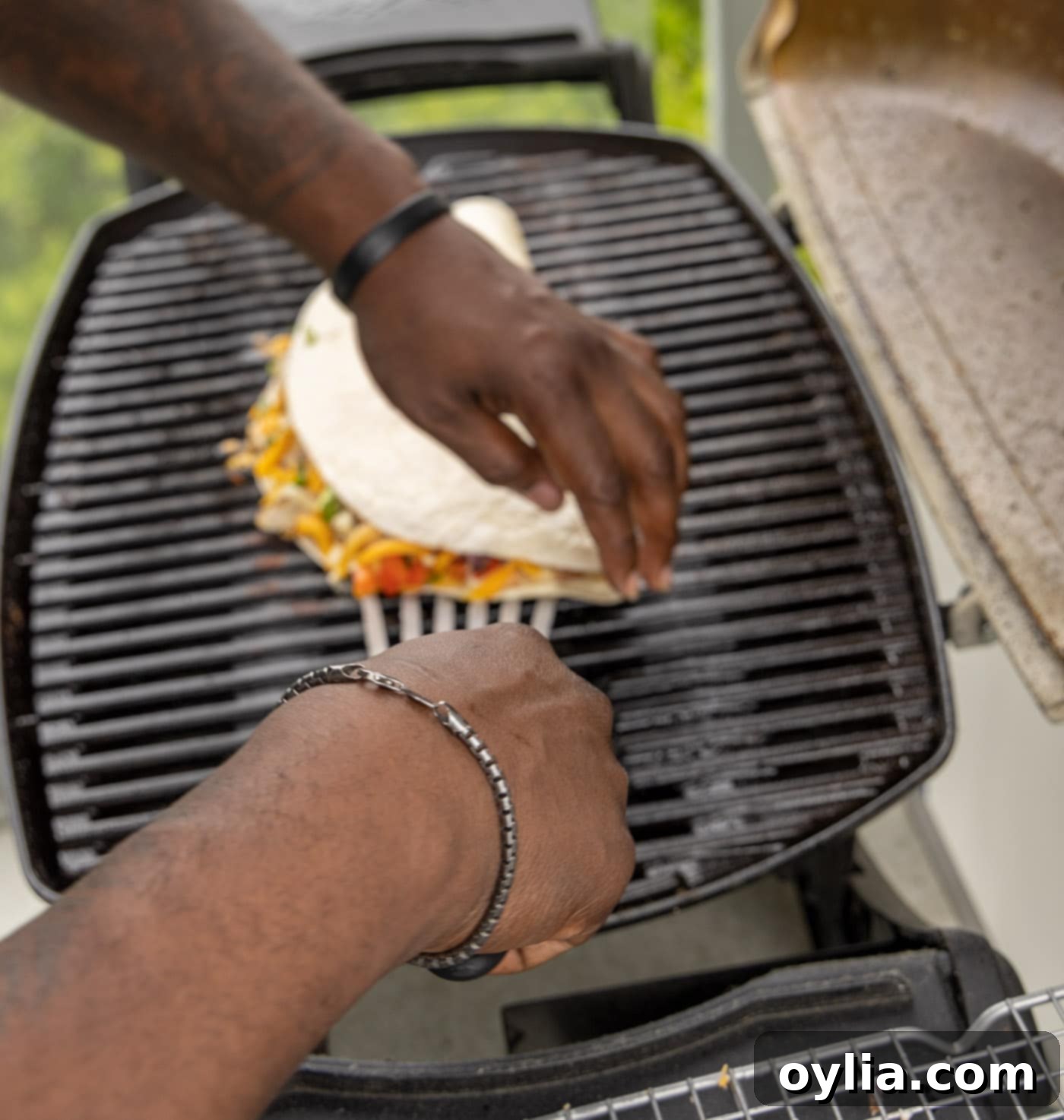 Flipping a chicken quesadilla on a barbecue grill with a spatula