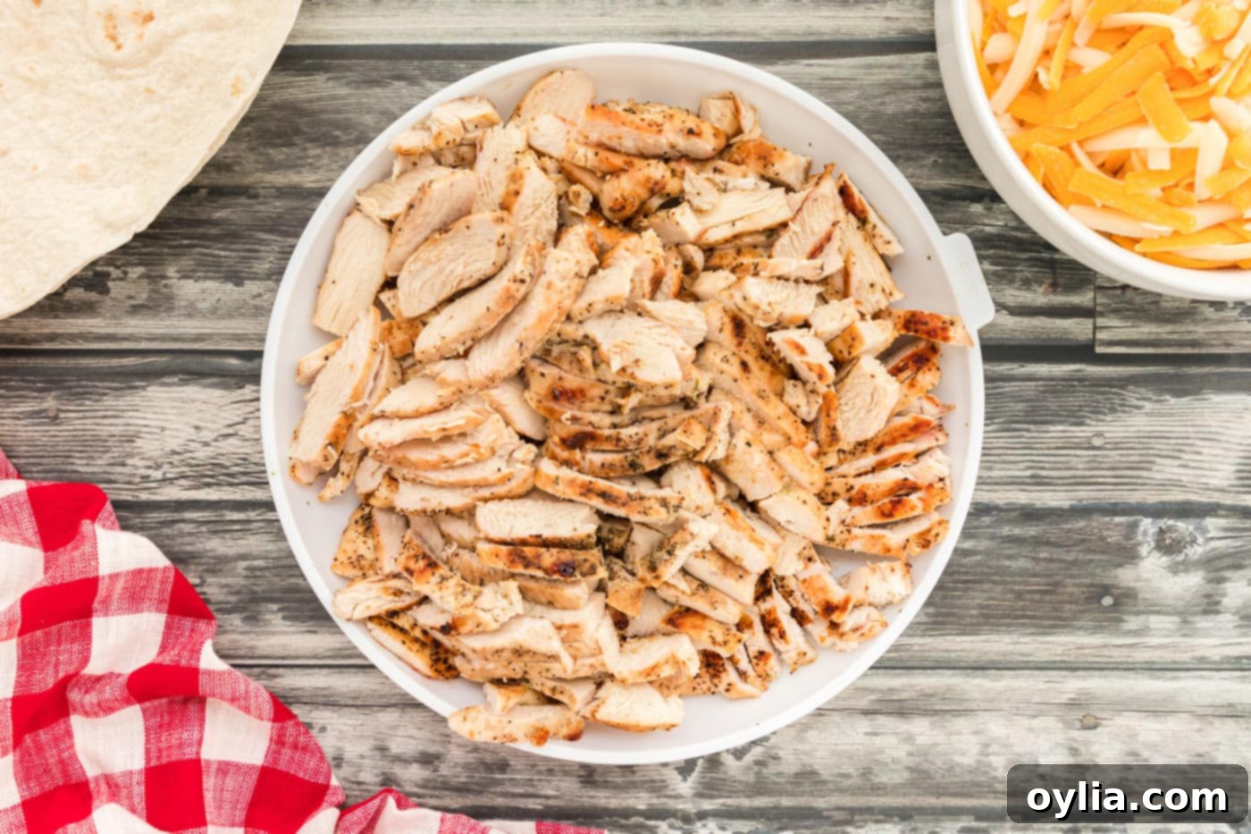 Cooked chicken breast, sliced into thin strips, in a white bowl