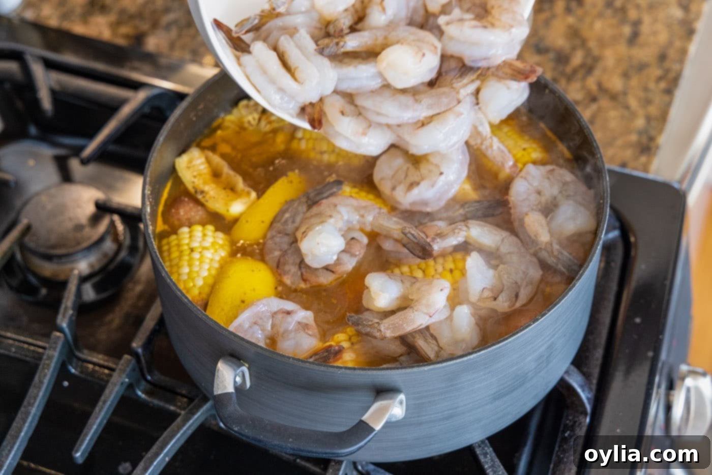adding shrimp to large pot of shrimp boil