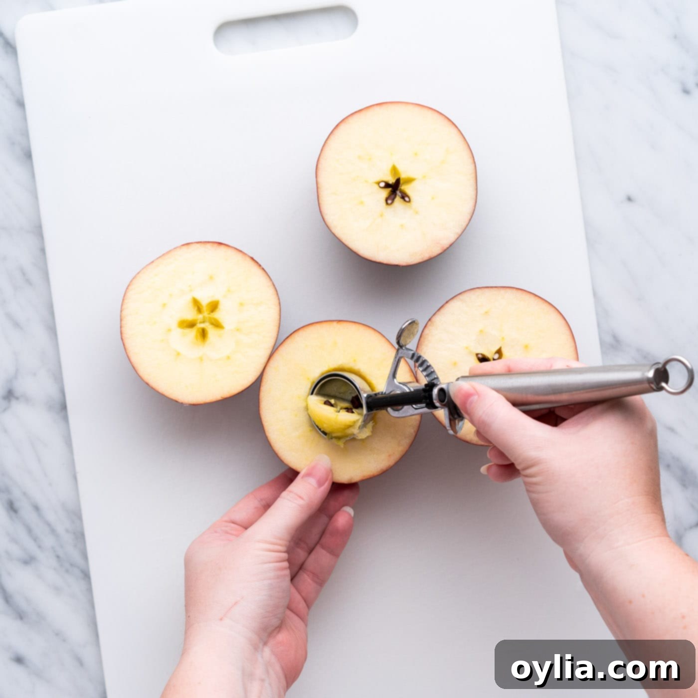 Coring apple halves on a cutting board