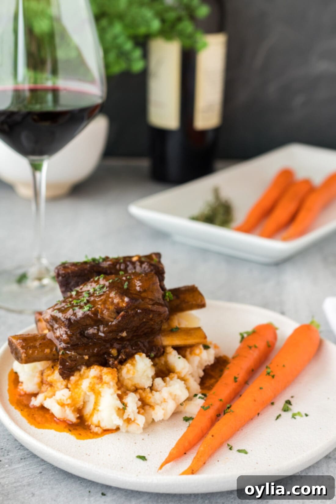 Instant Pot Beef Short Ribs on a plate with creamy mashed potatoes and fresh rosemary