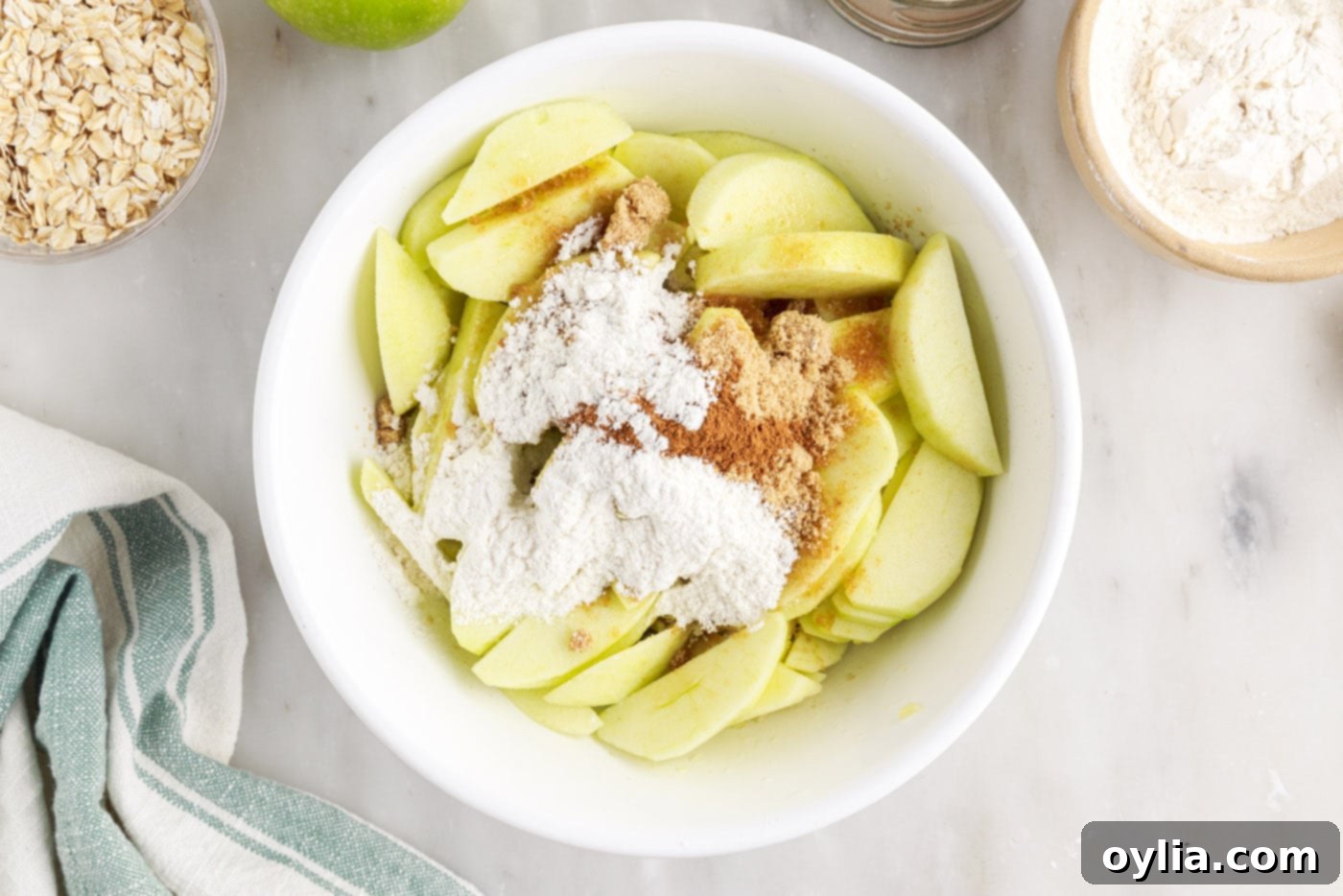 Sliced apples mixed with brown sugar, cinnamon, and flour in a bowl