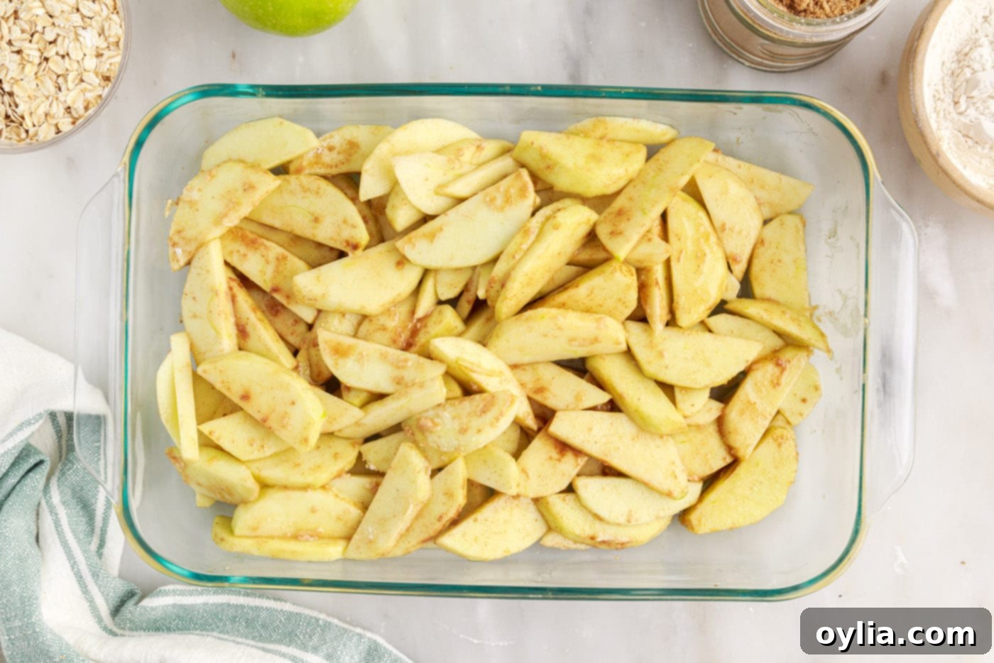 Spiced apple slices spread evenly in a baking dish, ready for topping