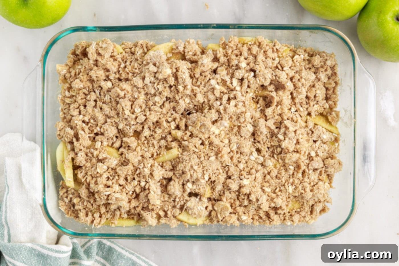 Apple crumble in a baking dish before baking, with topping evenly spread