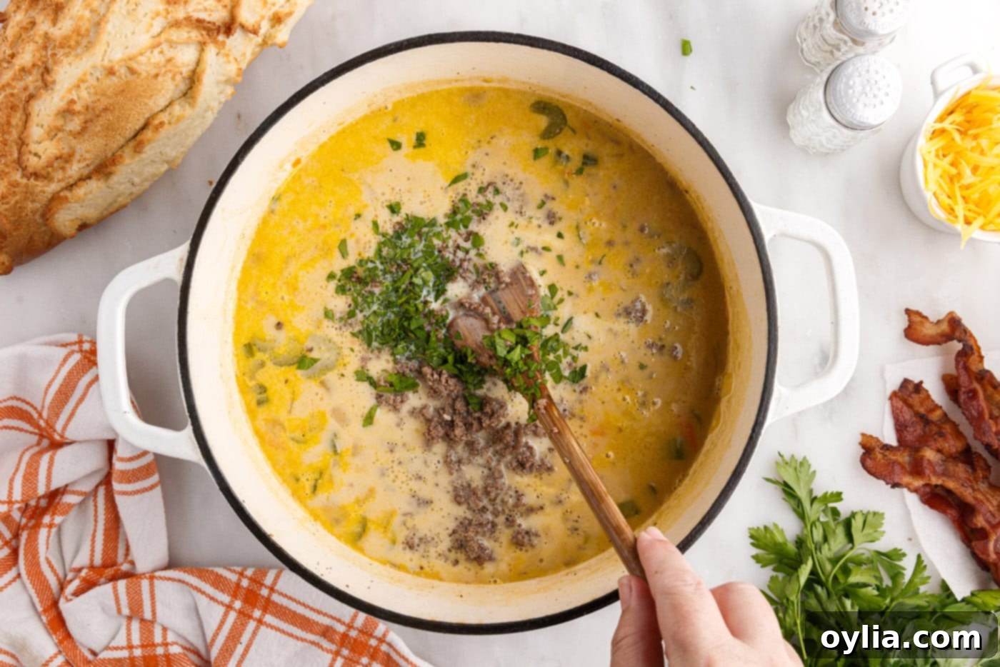 A large pot of finished creamy cheeseburger soup being stirred before serving