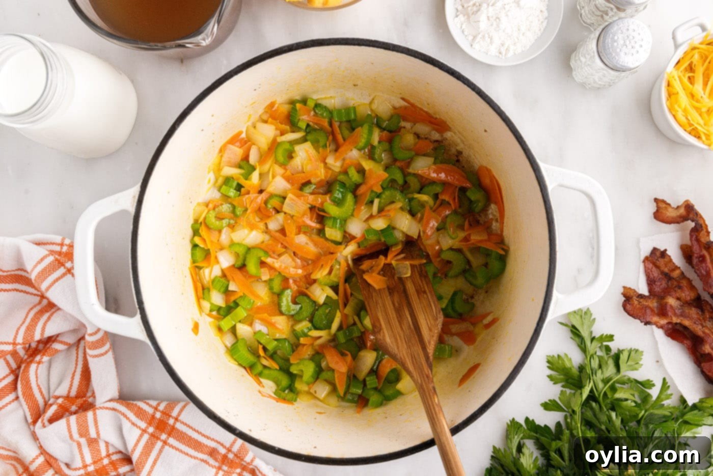 Sauteed vegetables in a stockpot with a wooden spoon, softened and ready for the next step