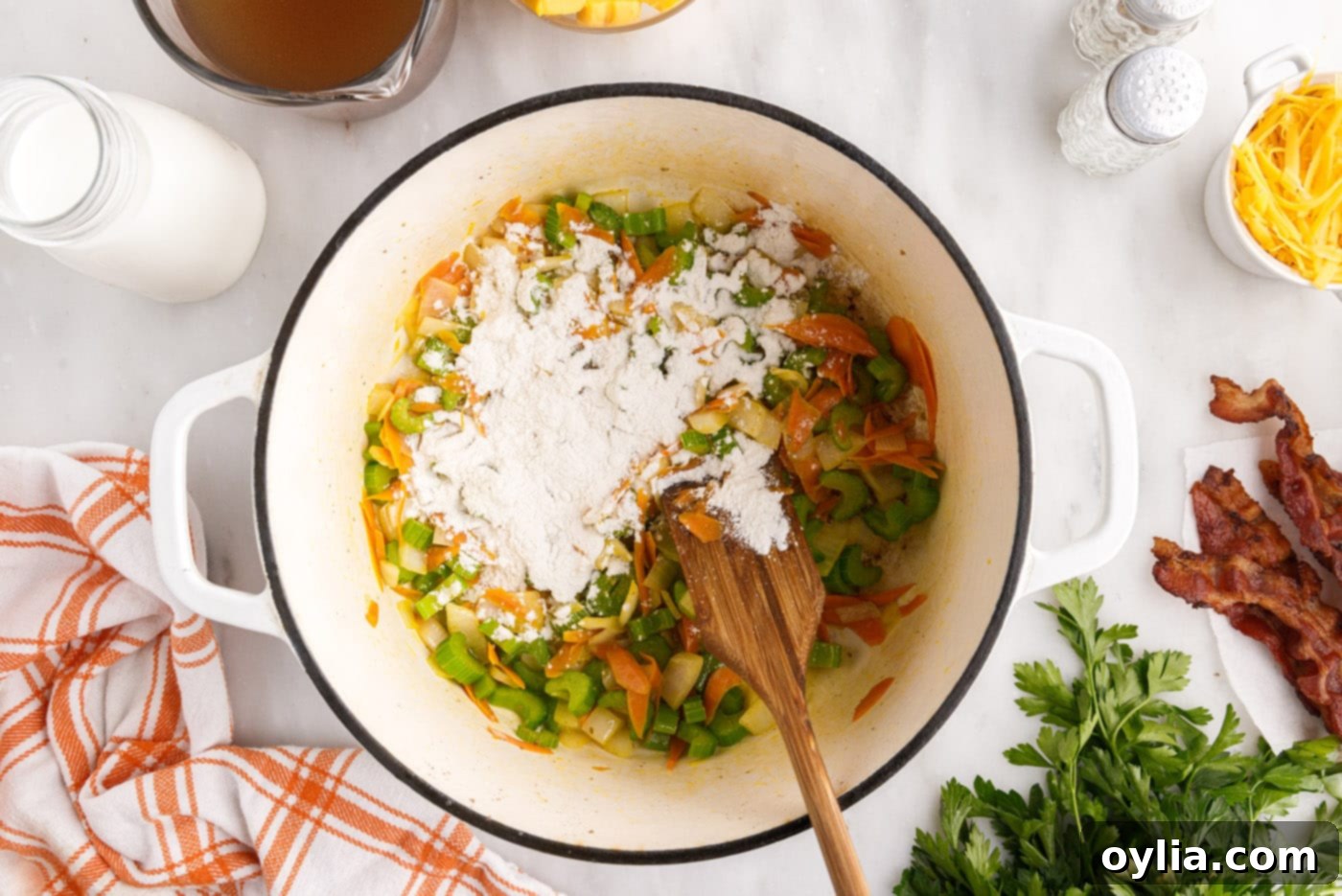 Sprinkling flour over sauteed vegetables in a stockpot and stirring