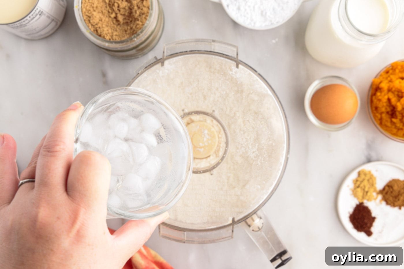 Pouring ice water into the food processor containing flour and butter mixture